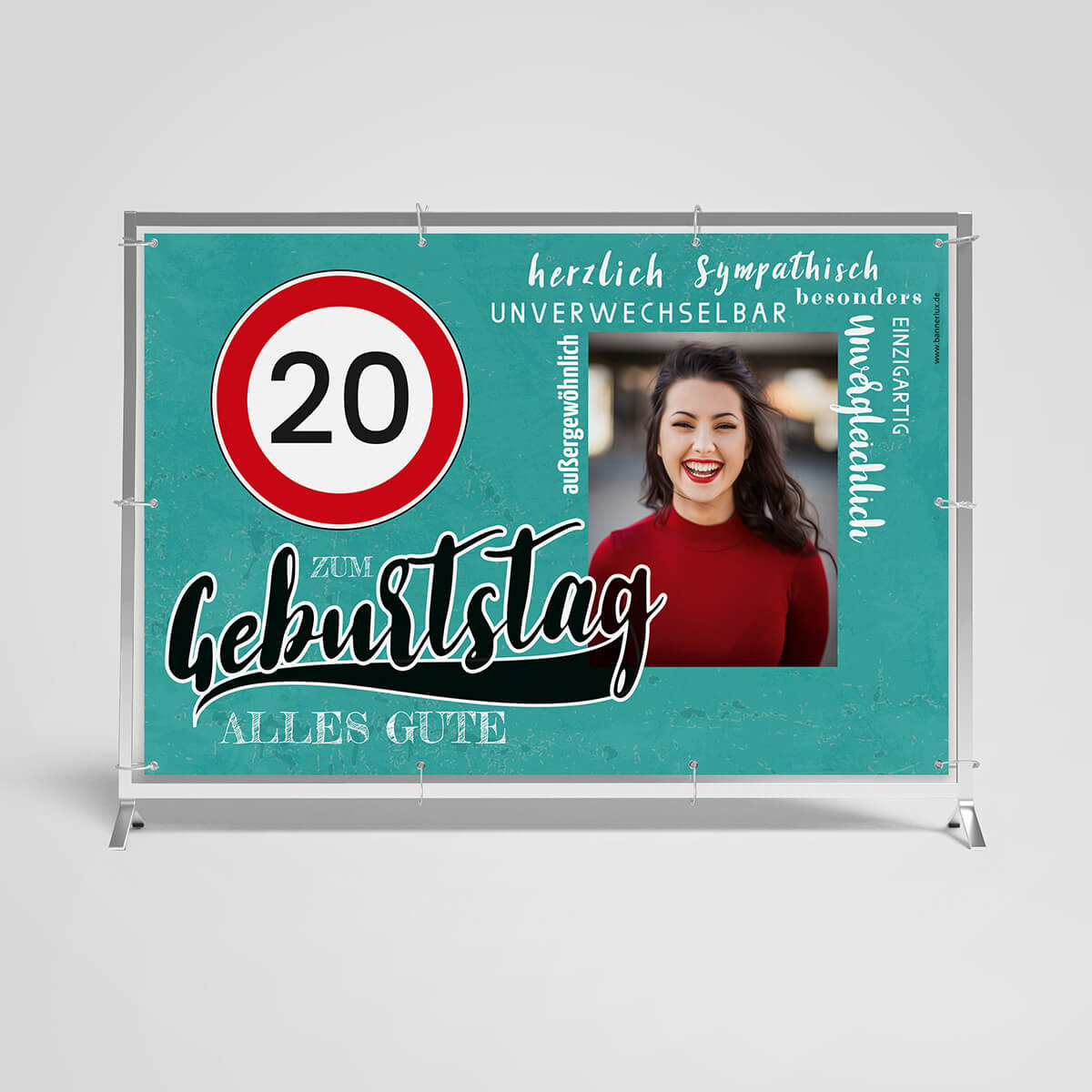 Geburtstagsbanner für den 20. Geburtstag. Türkisfarbener Hintergrund mit einem roten Verkehrsschild '20'. Zentral steht 'Zum Geburtstag Alles Gute' in großer Schrift. Rechts ist ein Foto einer lächelnden Frau in rotem Oberteil. Um das Bild herum stehen positive Adjektive wie 'herzlich', 'sympathisch', 'unvergesslich' und 'einzigartig'. Der Banner ist auf einem weißen Hintergrund mit einem Metallrahmen montiert.